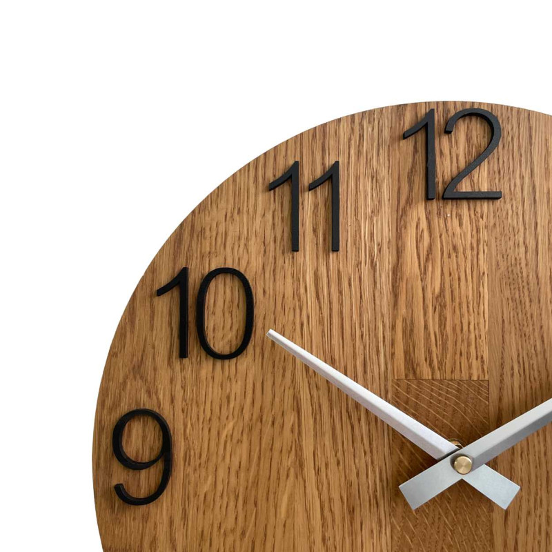 Wooden clock with a symmetrical shape and a cutout inspired by motifs from nature.